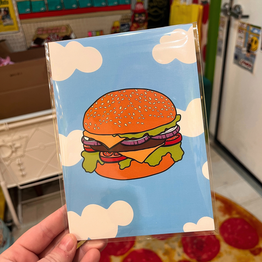 Illustration of a cheeseburger with lettuce, tomato, onions, and sesame bun floating in a bright blue sky with white clouds, 5x7 art print.